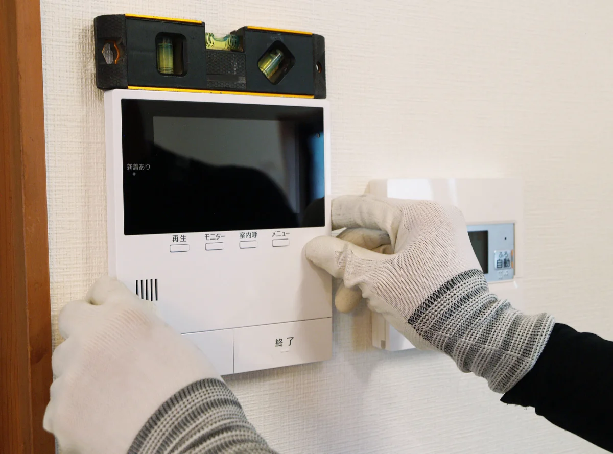 水平を確認しながらモニター付きインターホンを取り付ける作業
